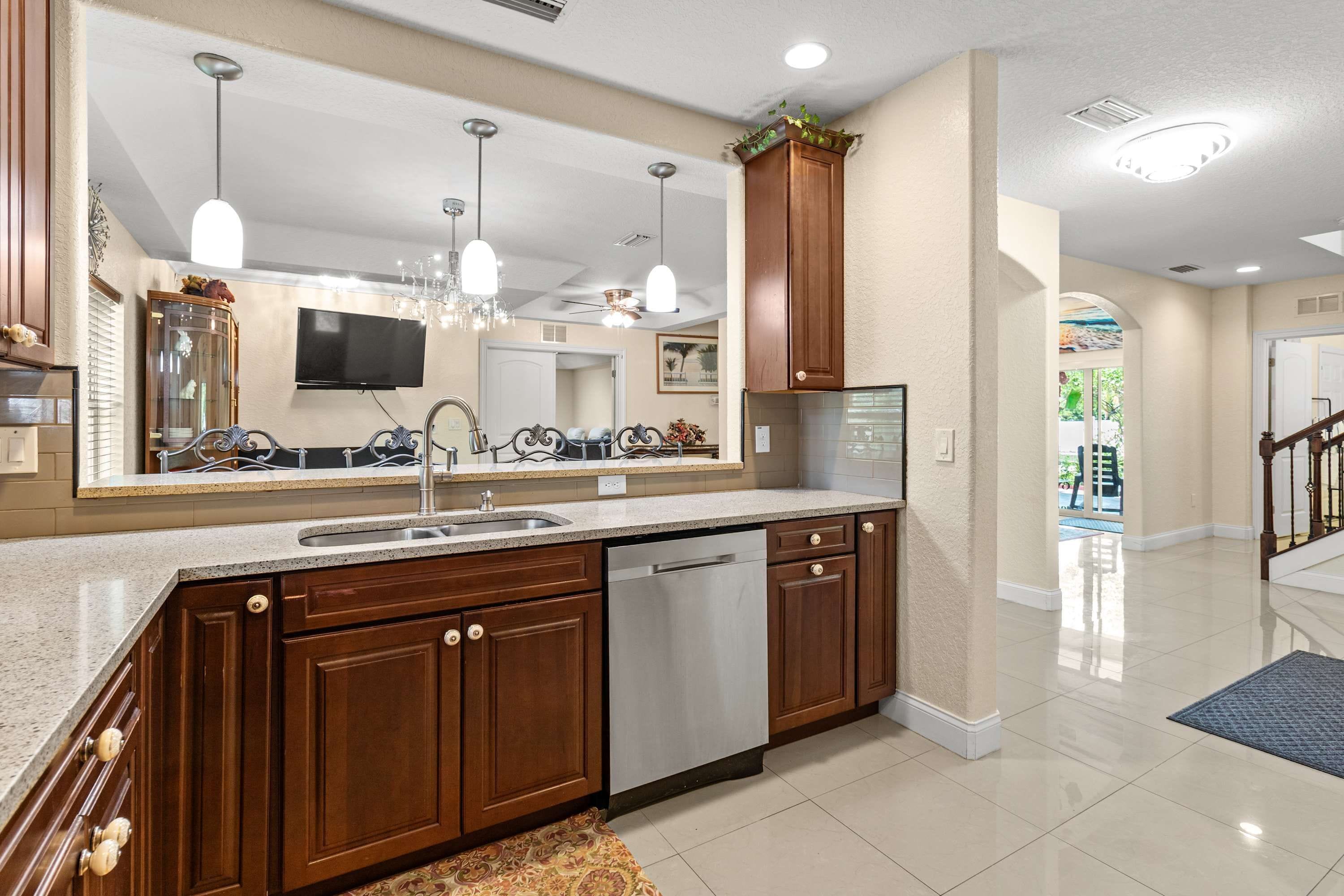 A modern kitchen with a large island, stainless steel appliances, and pendant lighting.