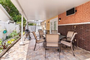 Eine Terrassenfläche mit Gartenmöbeln, einem Grill und einer Ziegelwand.