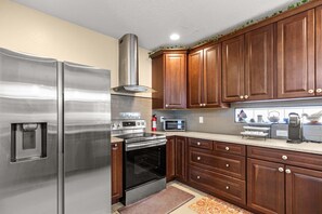 A kitchen with stainless steel appliances, wooden cabinets, and a tiled backsplash. - 4BR Escape 10 Mins to Madeira Clearwater Beach (Pinellas Park)