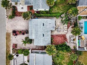Vista aérea de una propiedad residencial con piscina, un porche cubierto y diversa vegetación.