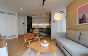 Uma sala de estar moderna com sofá, mesa de centro e área de jantar com cadeiras e mesa.
