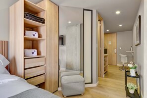 A modern hotel room with a bed, a wardrobe, a small stool, and a bathroom visible through an open door. - w Refined Loft w Balcony in Usaquen (Bogotá)