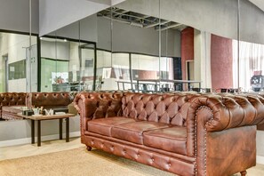 A spacious lounge area with leather sofas and a coffee table, large windows, and a high ceiling with exposed ductwork. - w Refined Loft w Balcony in Usaquen (Bogotá)