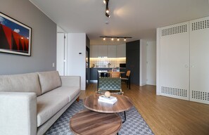 A modern living room with a sofa, two round wooden tables, and a kitchen in the background. - w Upscale 2BR With Balcony in Prime Miraflores (Lima)