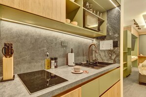 A modern kitchen with a black induction cooktop, a stainless steel sink, and a wooden cabinet. - w Charming Cozy 3BR in the Heart of Zona T (Bogotá)
