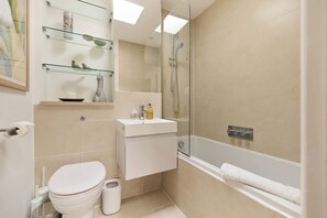 A modern bathroom with a glass shower enclosure, a white toilet, and a bathtub. - The Two-Bedroom Edit (Greater London)