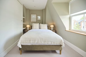 A bedroom with a bed, bedside lamps, a window, and a view of the outside. - The Two-Bedroom Edit (Greater London)