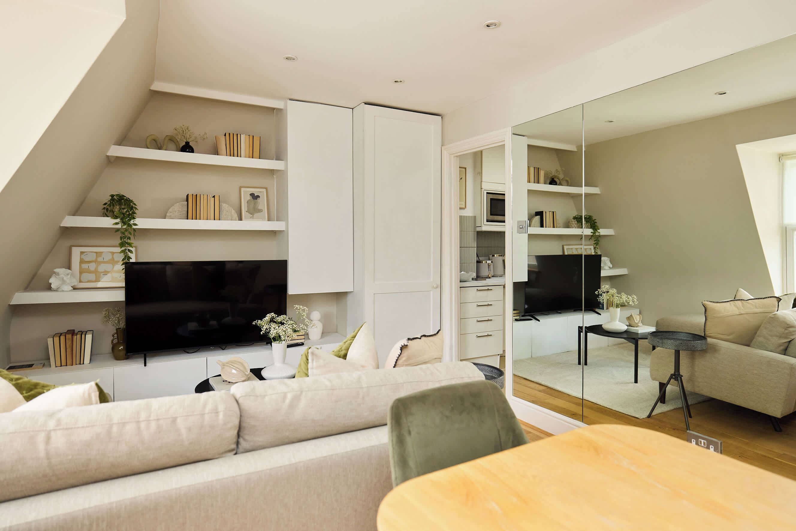 Een moderne woonkamer met een bank, een televisie en een eethoek met een tafel.