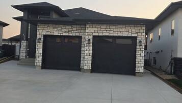 A modern two-story house with a stone facade and two black garage doors.