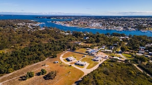 Vista aérea de un pueblo costero con un puerto deportivo, zonas residenciales y una combinación de terreno natural y urbanizado.