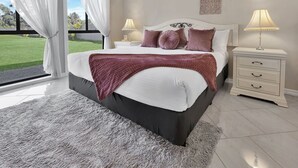 Ein Schlafzimmer mit einem Bett, Nachttischen, Blick ins Freie und dekorativer Wandgestaltung.