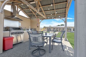 Une terrasse extérieure équipée d’un barbecue, de chaises et d’une table.