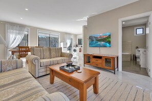 A modern living room with a sofa, a coffee table, and a television. - Slow down and enjoy island life at Le Grand Villa 2 (Raymond Island)