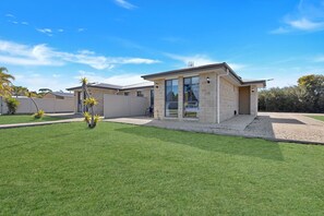 A modern two-story house with a well-maintained lawn and a fenced backyard. - Slow down and enjoy island life at Le Grand Villa 2 (Raymond Island)