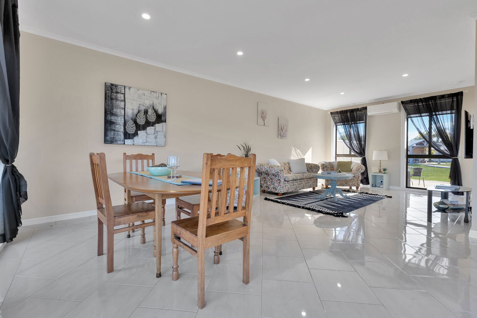 A spacious living area with a dining table, chairs, sofas, and a coffee table.