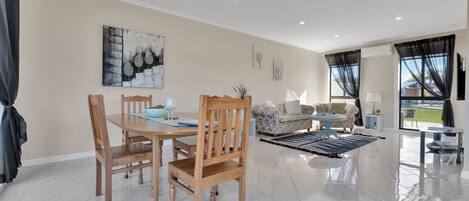 A spacious living area with a dining table, chairs, sofas, and a coffee table.