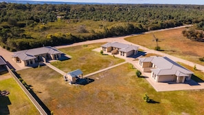 A residential area with multiple houses, a central open space, and surrounding forested land.