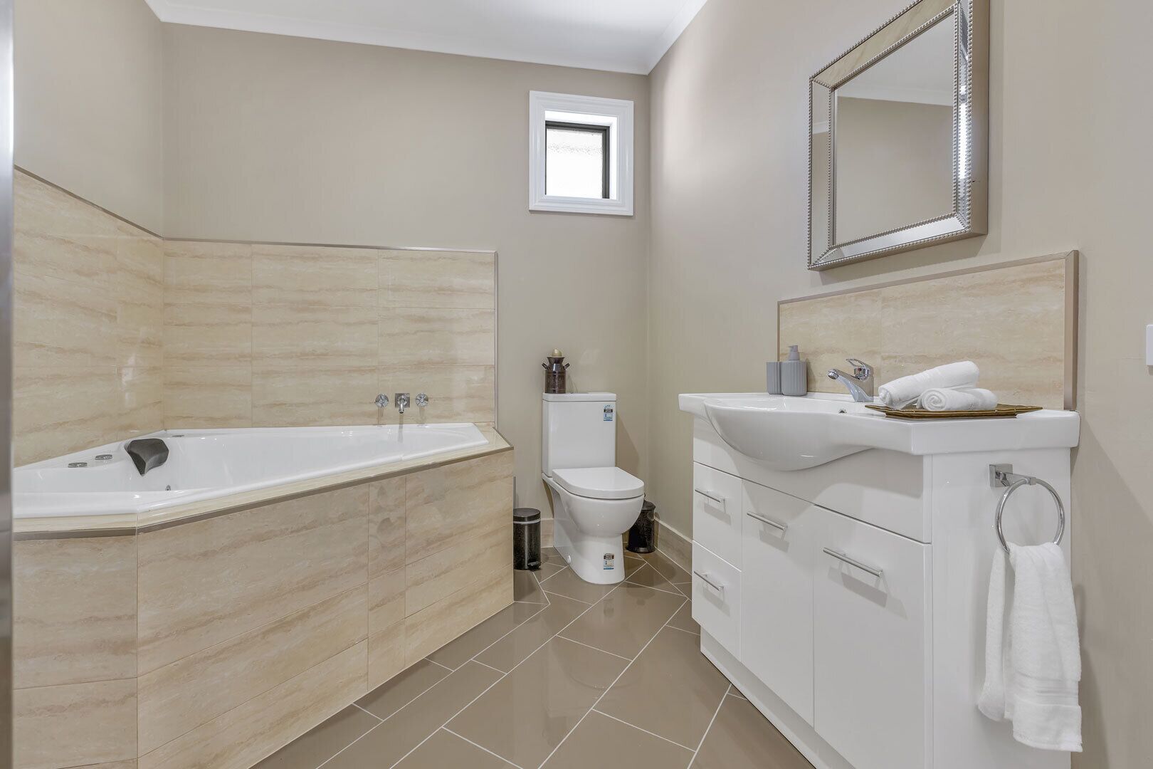 Une salle de bain moderne avec une baignoire sur pieds, des toilettes et un meuble-lavabo avec un évier et un miroir.