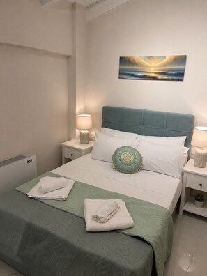 Een hotelkamer met een bed, twee nachtkastjes, een schilderij aan de muur en een radiator.