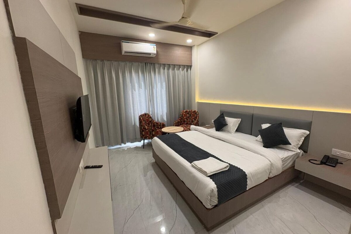 A modern hotel room with a large bed, a flat-screen TV, a desk, and a chair.