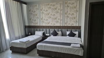 A hotel room with two beds, a large window with curtains, a ceiling fan, and a decorative wall panel.