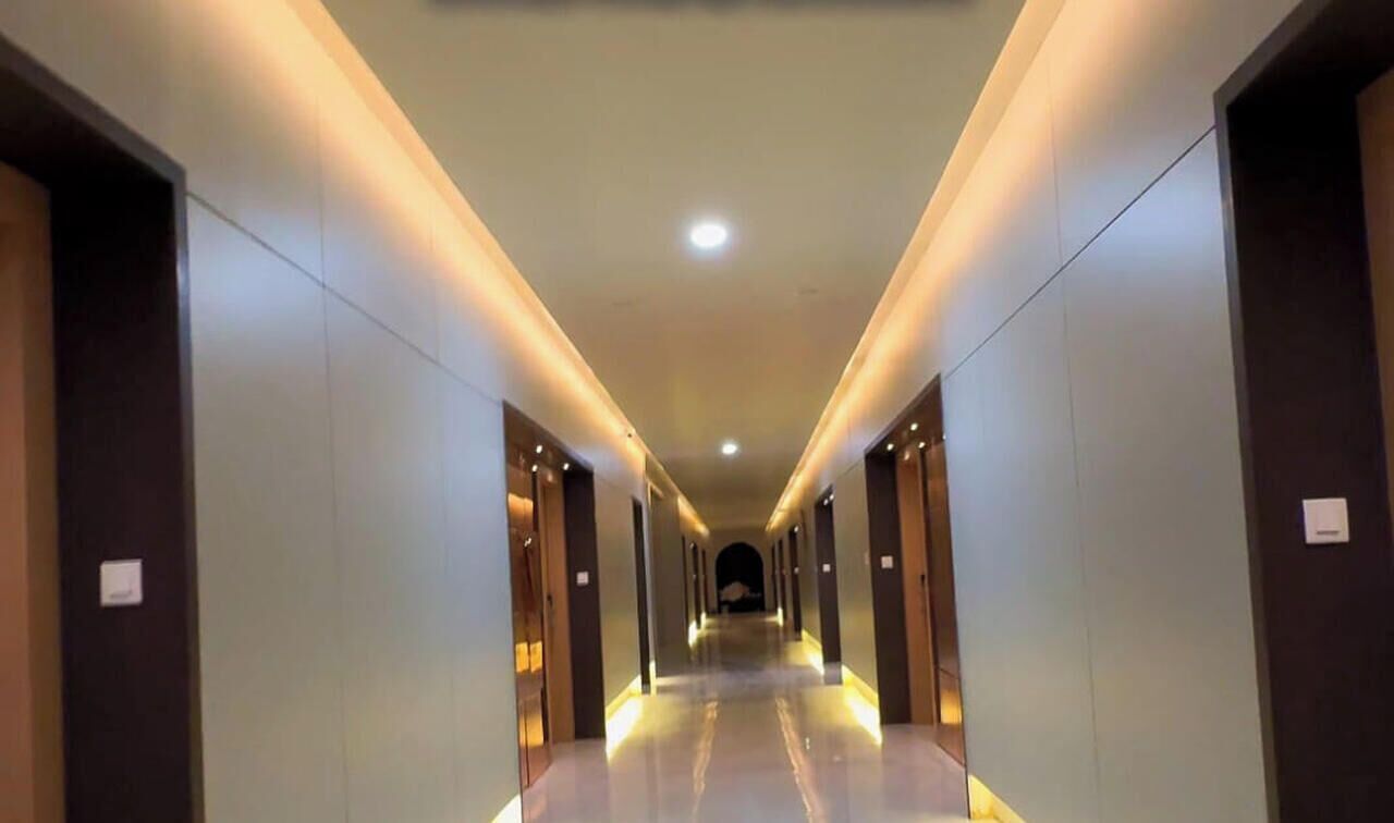 Un pasillo de hotel con un camino largo y recto, puertas a ambos lados y una lámpara en el techo.