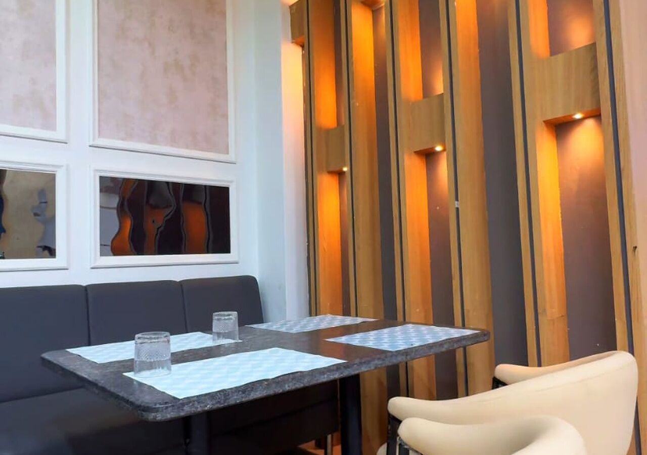 Un área de comedor con una mesa dispuesta para dos, un banco acolchado y un separador de madera con listones verticales.