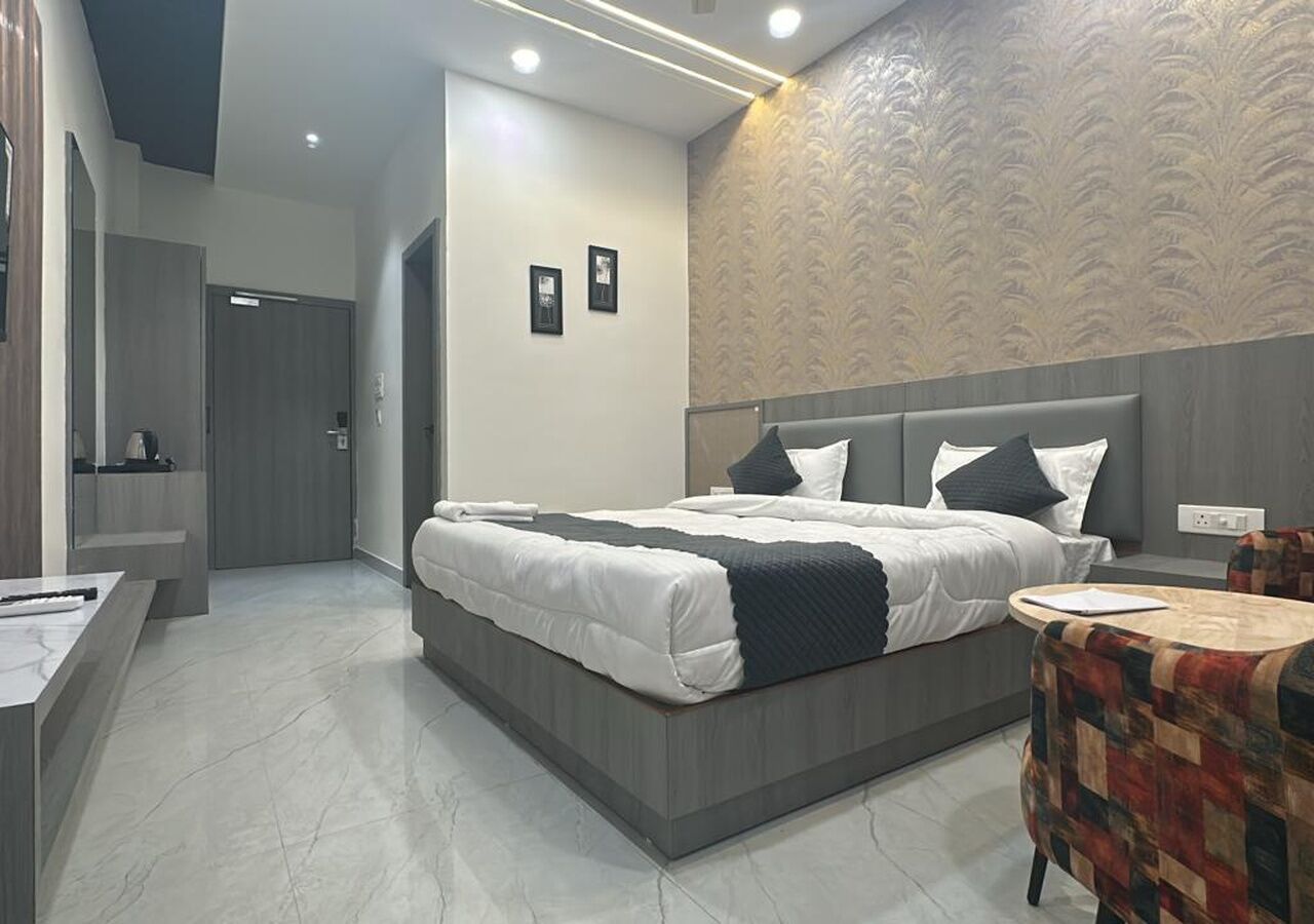 Een moderne hotelkamer met een groot bed, een klein rond tafeltje en een badkamer met een spiegel en toilet.