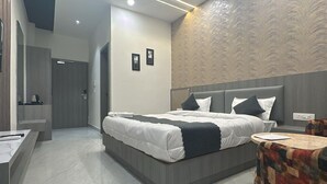 A modern hotel room with a large bed, a small round table, and a bathroom with a mirror and toilet.
