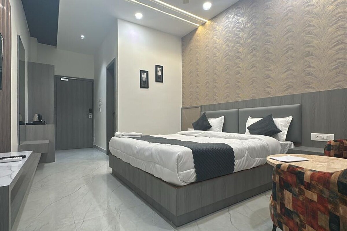 A modern hotel room with a large bed, a small round table, and a bathroom with a mirror and toilet.
