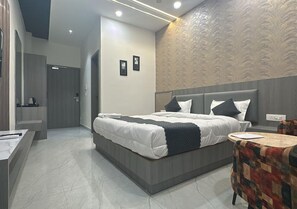 A modern hotel room with a large bed, a small round table, and a bathroom with a mirror and toilet. - Hotel Arena (Nasirabad)