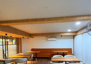 A modern interior with a wooden ceiling, a seating area with a sofa and tables, and an air conditioning unit on the wall. - Hotel Arena (Nasirabad)