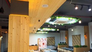 A restaurant interior with wooden ceiling beams, hanging plants, and tables set for dining.