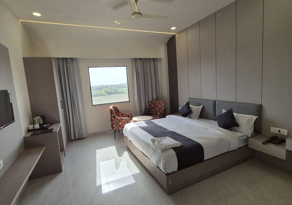 Una habitación de hotel moderna con una cama grande, un escritorio, una silla y un televisor.