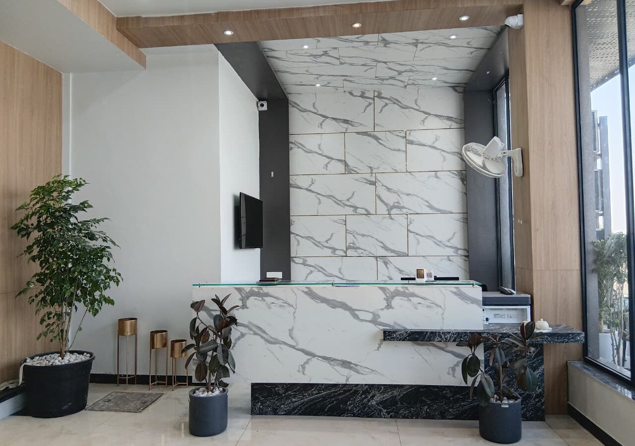 Een moderne receptie met marmeren wanden, een glazen balie en potplanten.