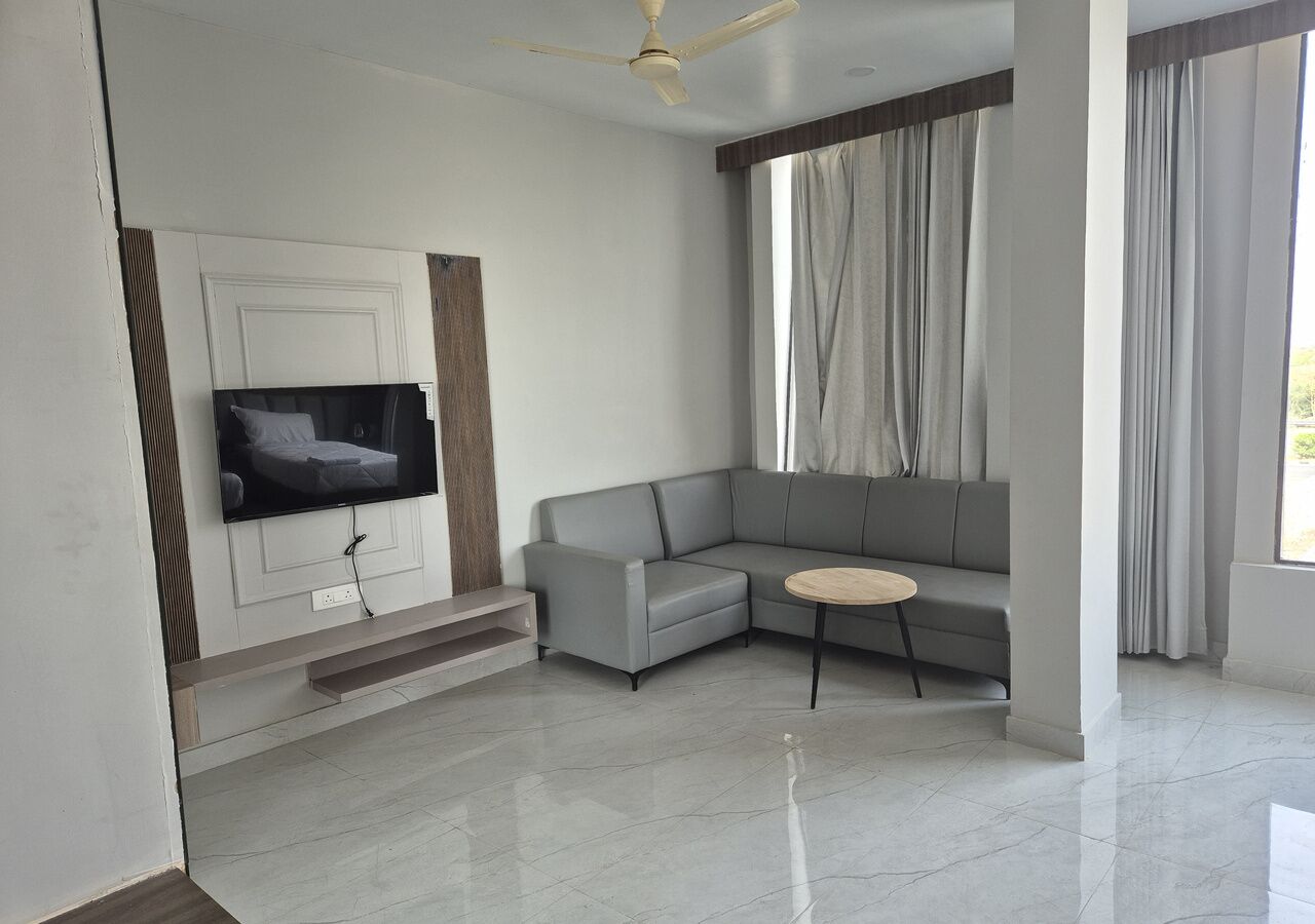 Una sala de estar moderna con un televisor de pantalla plana, un sofá seccional gris, una mesa redonda de centro y un ventilador de techo.