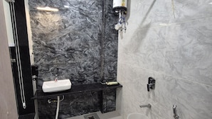 A bathroom with a marble sink, a handheld showerhead, and a toilet.