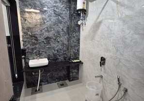 A bathroom with a marble sink, a handheld showerhead, and a toilet. - Hotel Arena (Nasirabad)