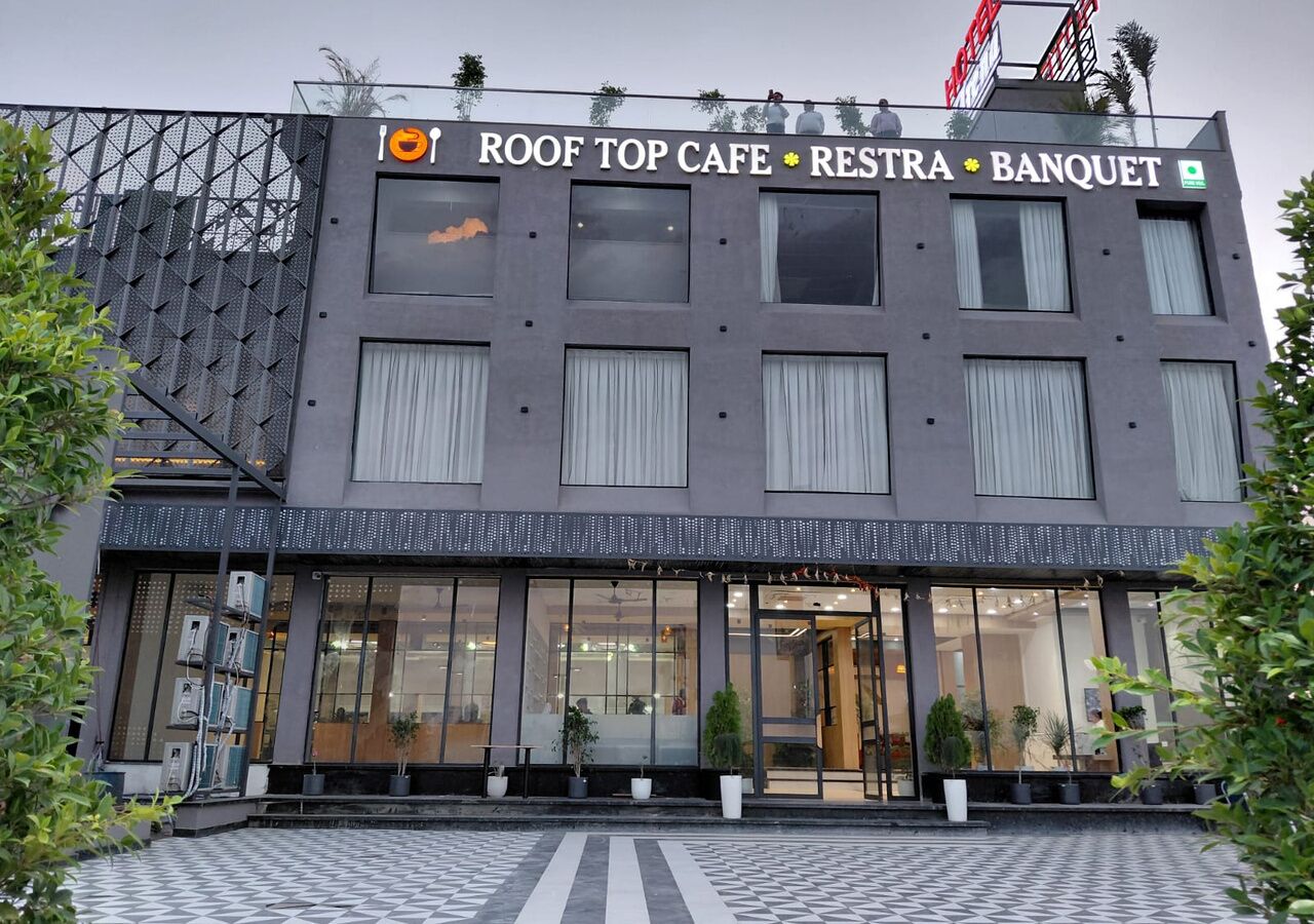 Een modern gebouw met een bord waarop staat 'ROOF TOP CAFE RESTRA BANQUET'.