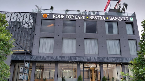 A modern building with a sign reading 'ROOF TOP CAFE RESTRA BANQUET.'