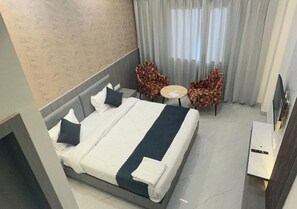 Habitación de hotel con una cama, dos sillas, una mesita y un televisor.