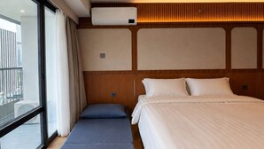 Una habitación con cama, un banco y una ventana con cortinas.