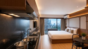 Una habitación de hotel moderna con cocina, una cama grande, zona de comedor y vistas a la ciudad.