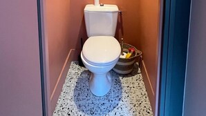 A small, narrow bathroom with a white toilet, a tiled floor, and a ceiling light. - Charming house in the city center (Angoulême)