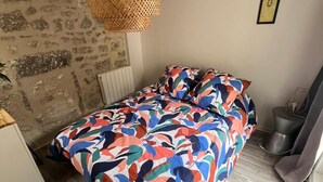 A bedroom with a bed, a hanging light fixture, a radiator, and a painting on the wall. - Charming house in the city center (Angoulême)