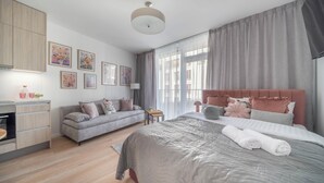 A modern bedroom with a large bed, a sofa, a desk, and a dining area. - Apartment Krochmalna 61 (Warszawa)