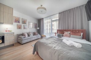 A modern bedroom with a large bed, a sofa, a desk, and a dining area. - Apartment Krochmalna 61 (Warszawa)