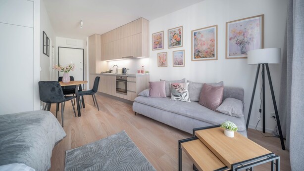 A modern living room with a sofa, a dining table, and a kitchen area with wooden cabinets. - Apartment Krochmalna 61 (Warszawa)
