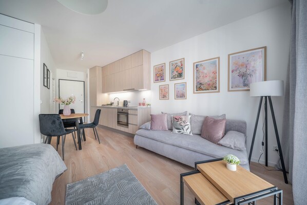 A modern living room with a sofa, a dining table, and a kitchen area with wooden cabinets. - Apartment Krochmalna 61 (Warszawa)