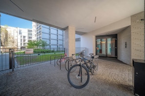 A covered outdoor area with a bike rack, a sign for 'BOAT,' and a building entrance with glass doors. - Apartment Krochmalna 61 (Warszawa)